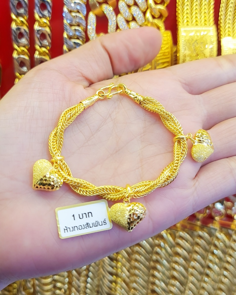 Close-up of a 23K Thai Gold Bracelet (1 Baht weight) featuring a braided rope chain and multiple dangling heart-shaped charms.