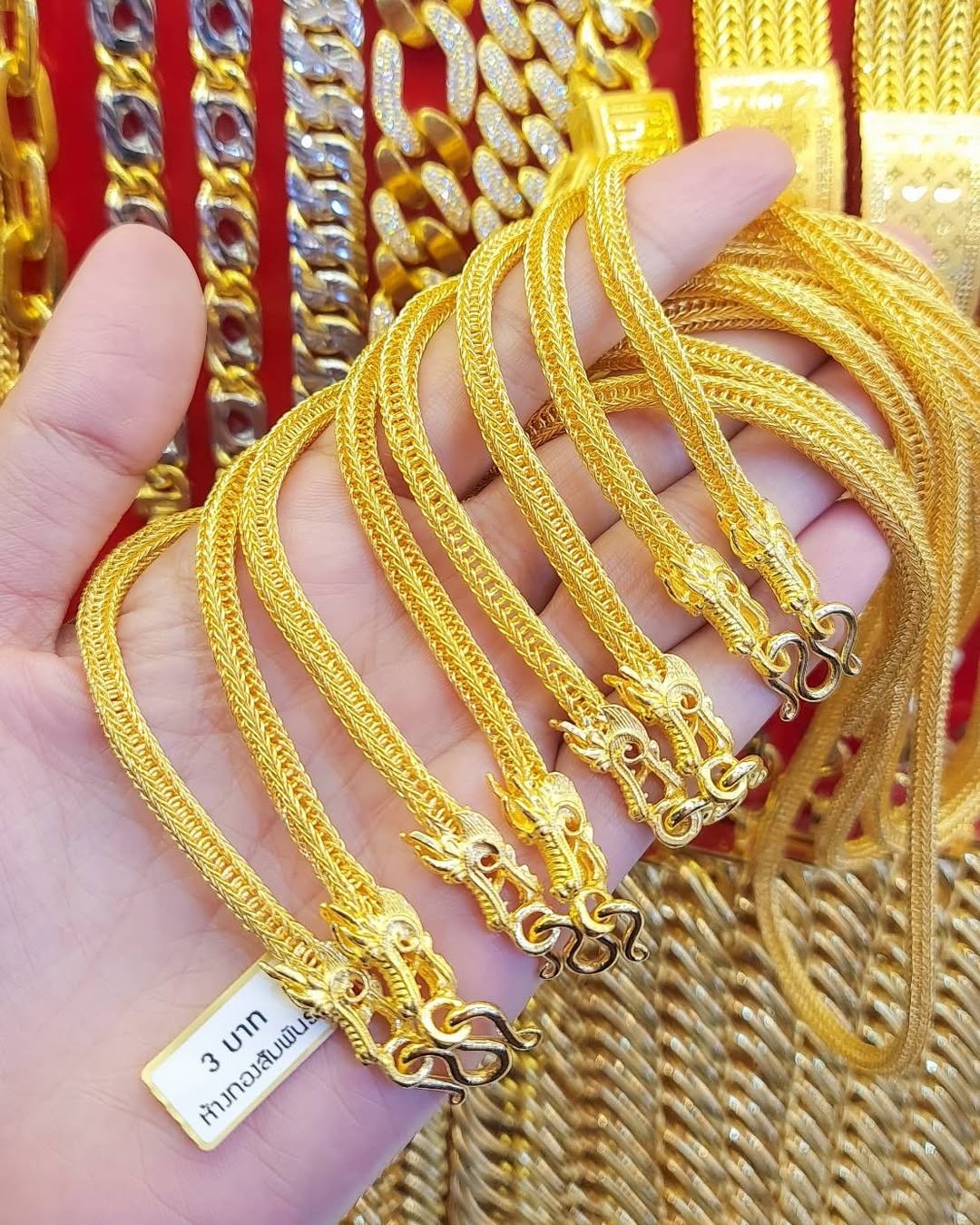 Hand holding multiple 3 Baht 23K Gold Chains with intricate mesh weave and ornate dragon head clasps.